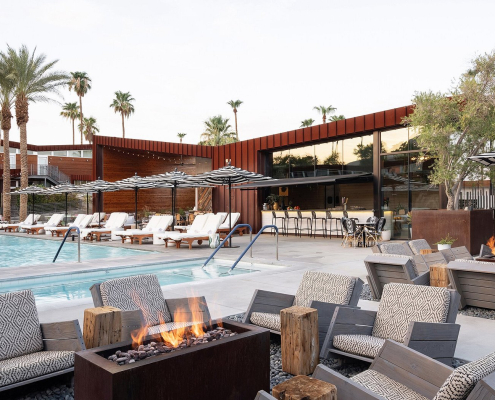 Several chairs and fire pits next to the pool on an overcast day at Arrive Palm Springs