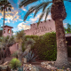 The front of Hotel California with a palm tree in the foreground and another palm in the background at sunset on a cloudy day