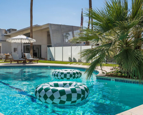 Green and white checkerboard inner tubes float on the water in the pool at The Monkey Tree Hotel in Palm Springs, California