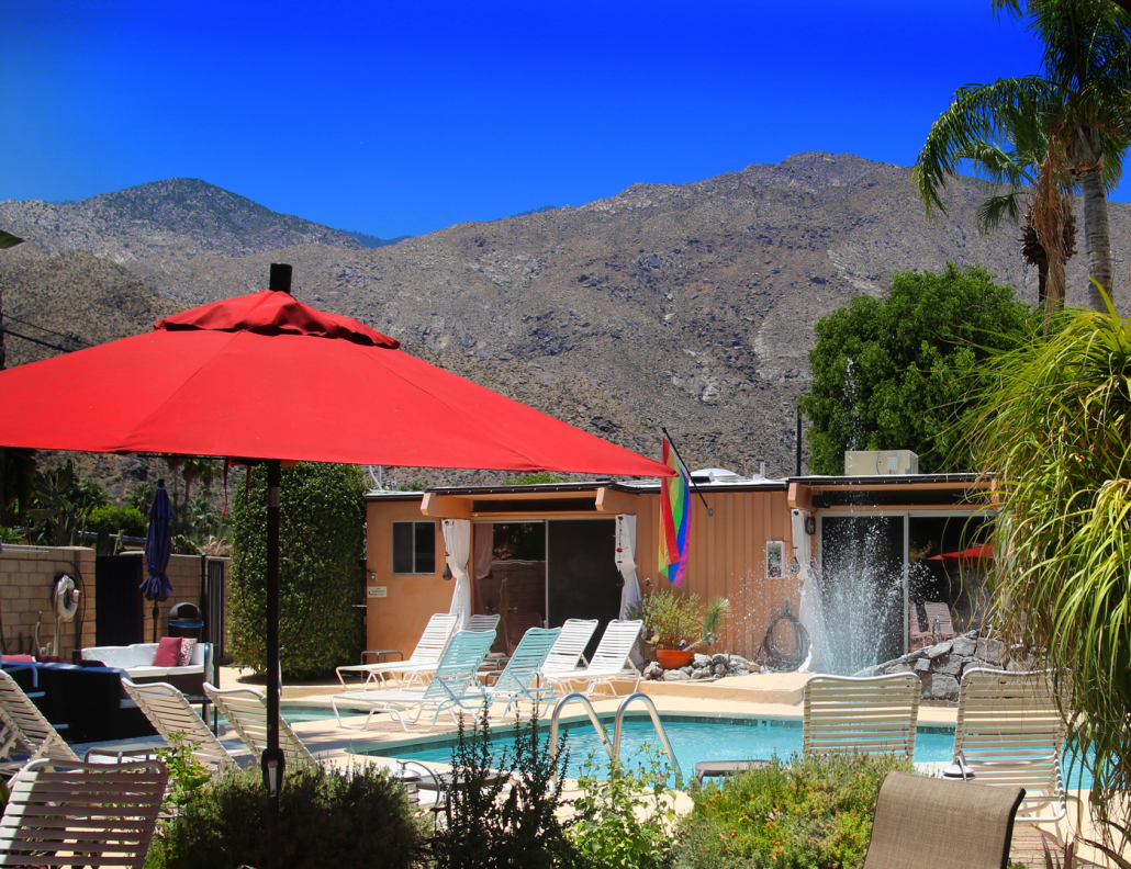 A rainbow flag hangs proudly above the pool at Triangle Inn Palm Springs, a men's clothing-optional boutique hotel in Palm Springs, California