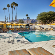 Bright yellow umbrellas shade loungers around the beautiful large pool at Twin Palms men's clothing-optional resort in Palm Springs, California