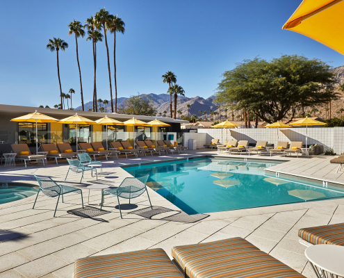 Bright yellow umbrellas shade loungers around the beautiful large pool at Twin Palms men's clothing-optional resort in Palm Springs, California