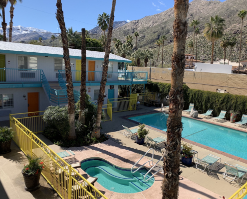 The pool and kidney-shaped spa in the courtyard at Adara Hotel Palm Springs on a sunny day