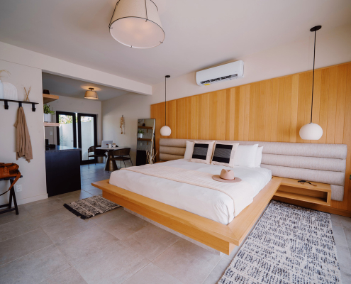 A large king bed with a white comforter is in the center of a room at Azure Sky Hotel in Palm Springs, California