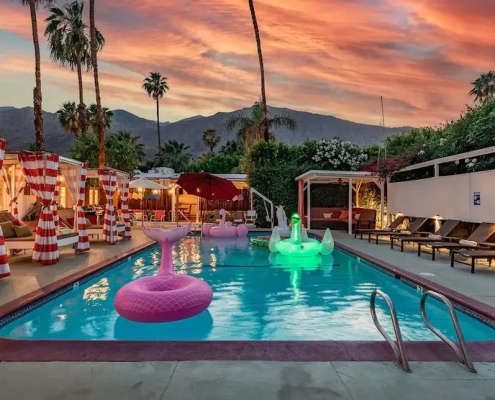 A light up swan pool float in the pool at Float Hotel Palm Springs at dusk with clouds in the sky