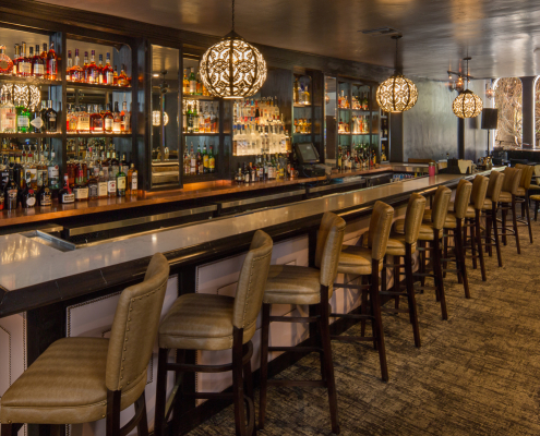 The long bar with leather seats lined up in front of it at Melvyn's Bar in the Ingleside Estate in Palm Springs