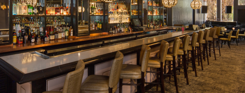 The long bar with leather seats lined up in front of it at Melvyn's Bar in the Ingleside Estate in Palm Springs