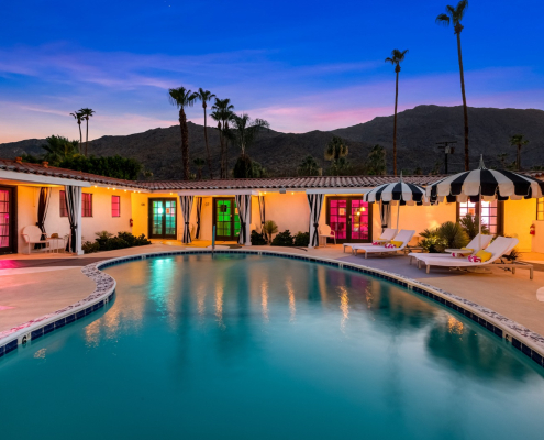 The pool at the Spirit of Sofia hotel in Palm Springs, California, in the evening with colored lights on in the room windows