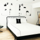 A white comforter on a black bed frame under a black and white artwork at The Jazz Hotel Palm Springs