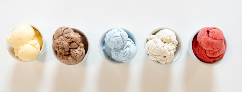 Five bowls of colorful ice cream lined up in white bowls