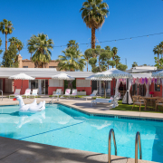 A white swan float in the pool at The Muse Palm Springs on a clear blue sky day