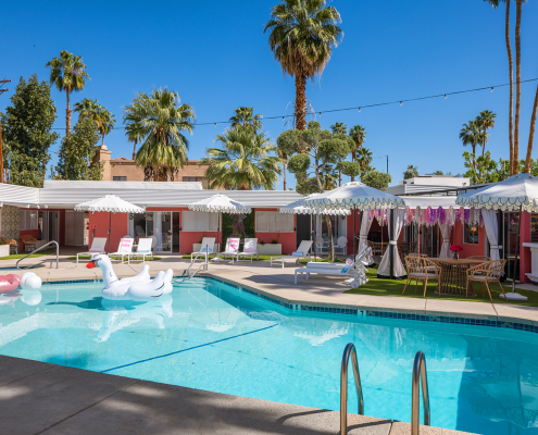 A white swan float in the pool at The Muse Palm Springs on a clear blue sky day