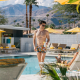 Two men smile at each other while hanging out by the pool on a sunny day at Twin Palms Resort in Palm Springs, California