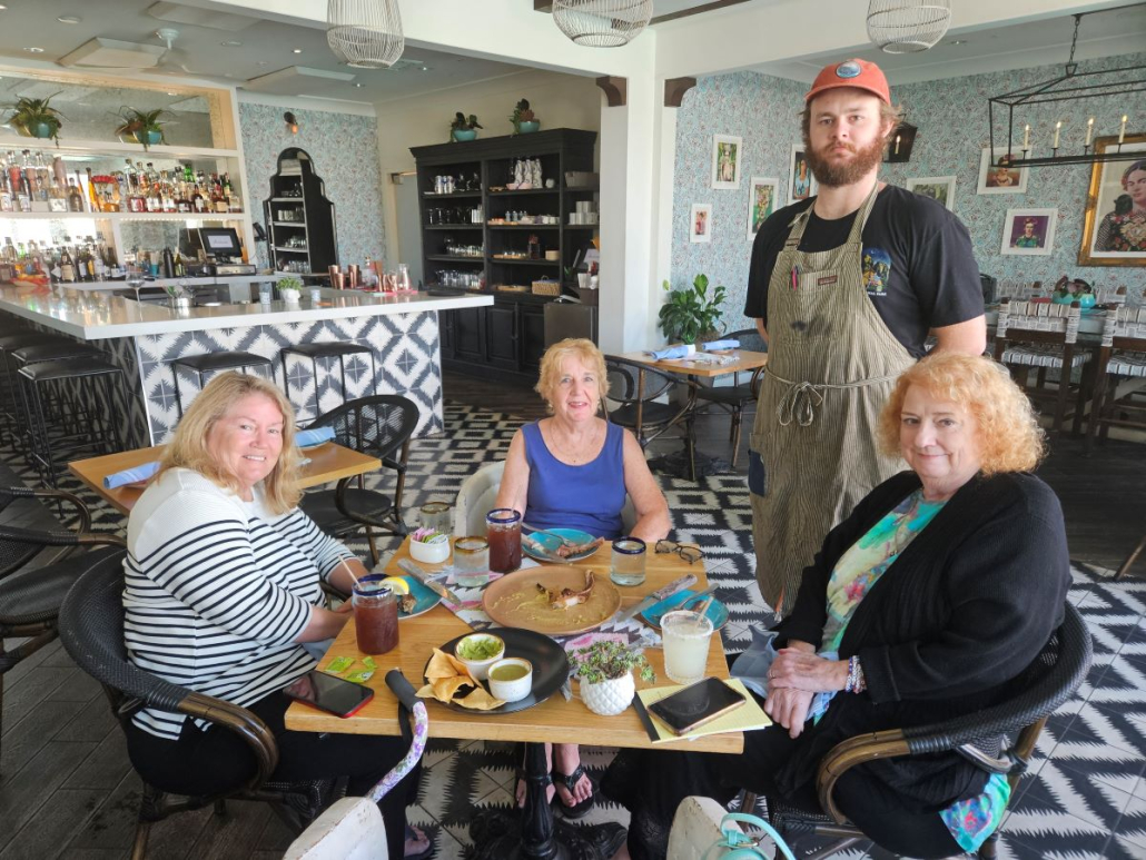 Three women sit at a table inside Azucar Restaurant in Palm Springs, California, with the chef standing next to them