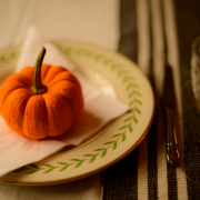 A small orange pumpkin on a white napkin on a plate on a table