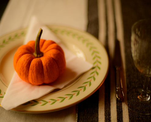 A small orange pumpkin on a white napkin on a plate on a table