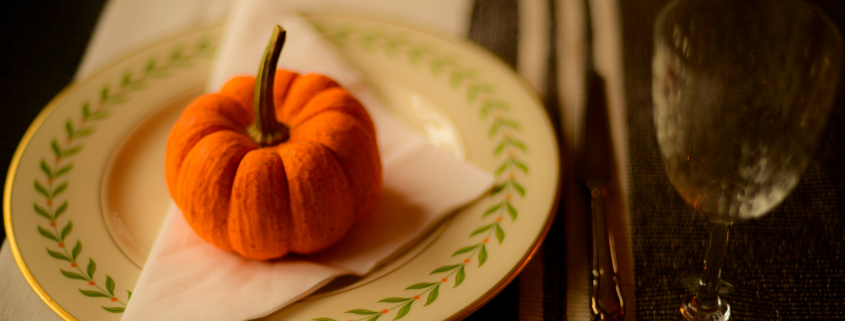 A small orange pumpkin on a white napkin on a plate on a table