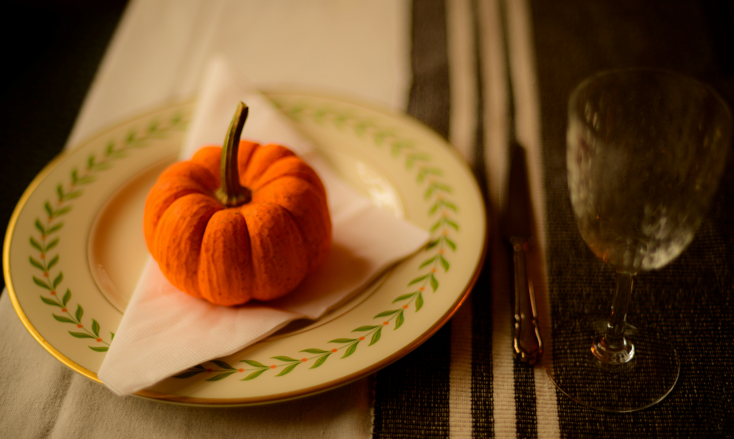 A small orange pumpkin on a white napkin on a plate on a table