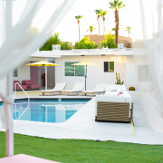 The pool at The Cactai in Palm Springs surrounded by cabanas and palm trees