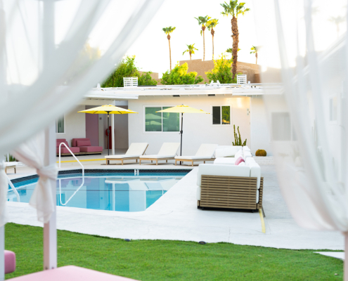 The pool at The Cactai in Palm Springs surrounded by cabanas and palm trees