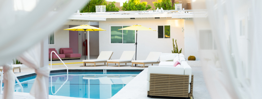 The pool at The Cactai in Palm Springs surrounded by cabanas and palm trees