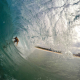 A person rides an ocean wave on a surfboard