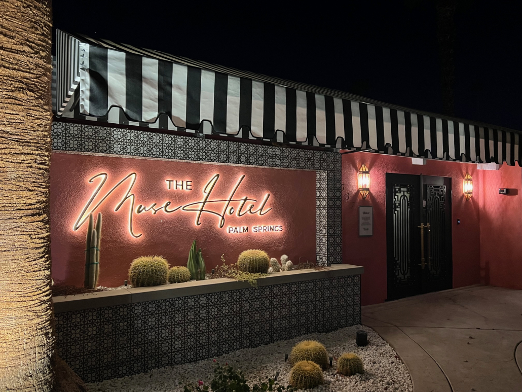 The entrance to The Muse Hotel with the sign lit up at night