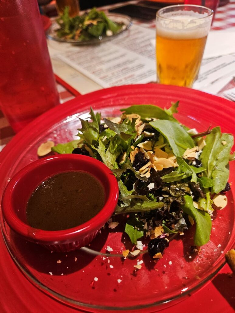 A red plate with salad on it from Bill's Pizza