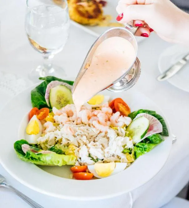 A woman pours dressing on her shrimp and crab Louis salad at Ingleside Inn in Palm Springs, California