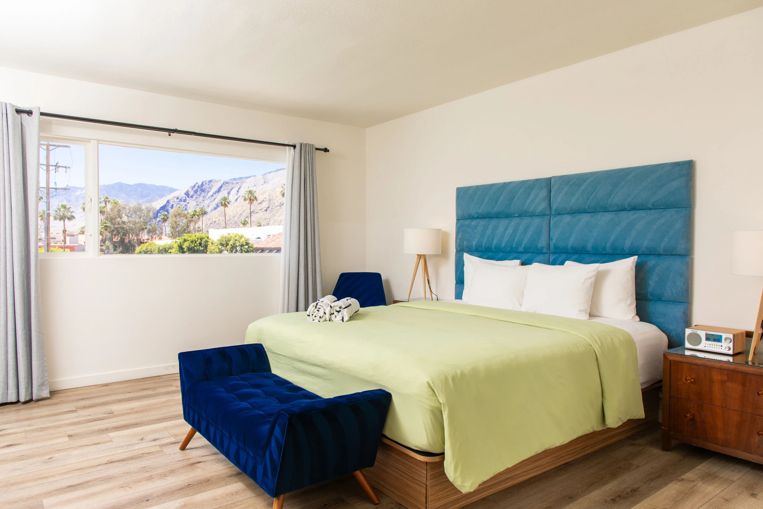 A blue headboard and green comforter in a spacious room at Skylark Hotel Palm Springs