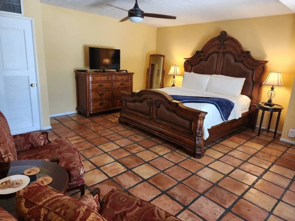 A room at the La Maison Hotel in Palm Springs has a large king-sized bed with wooden frame and tiled floors