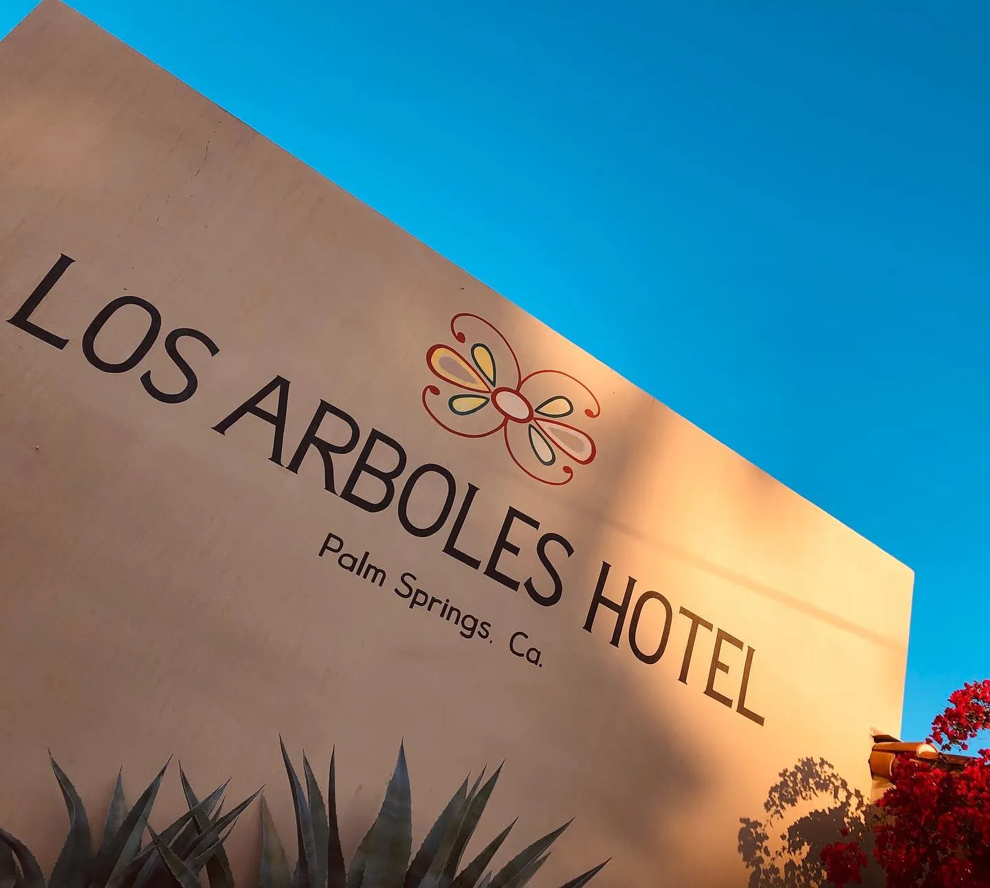 The words "Los Arboles Hotel" are painted in black on the side of the Los Arboles Hotel
