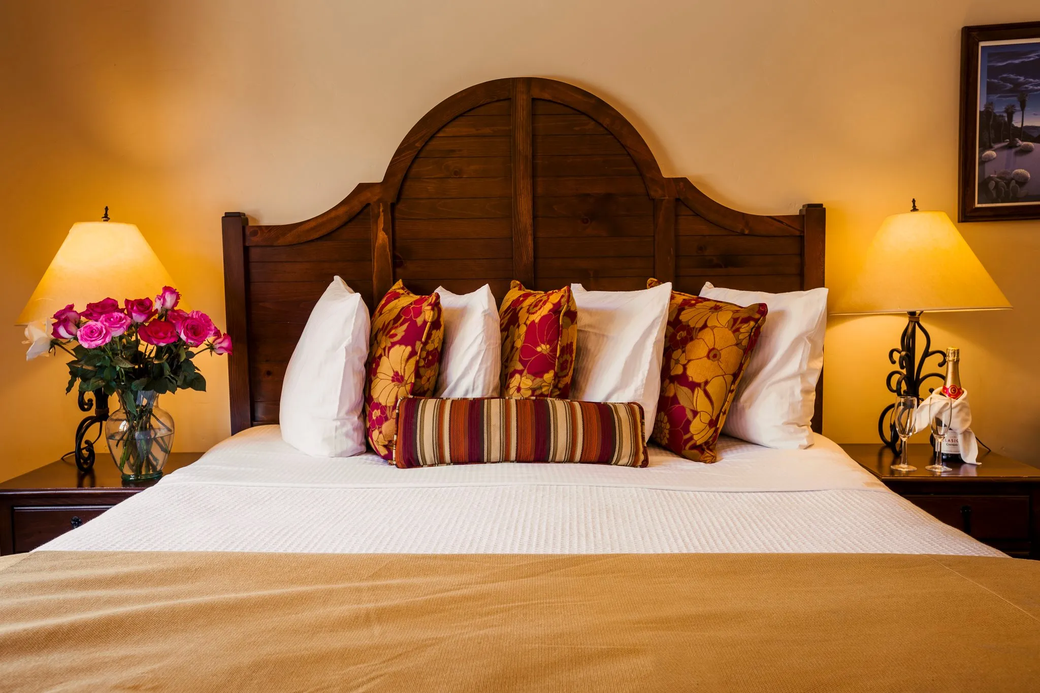 A brown headboard with white sheets and colorful pillows in a room at the Los Arboles Hotel in Palm Springs, California