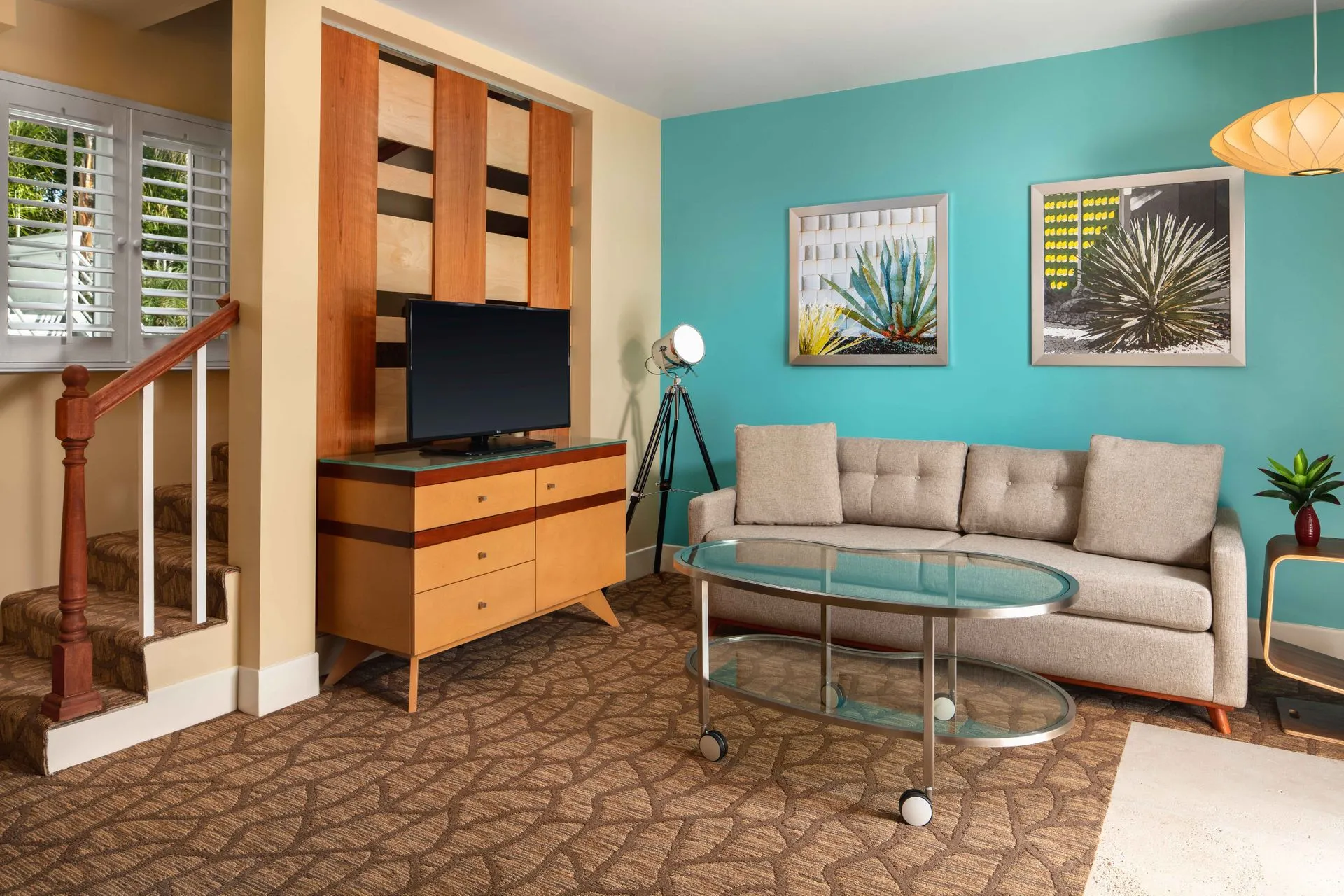 A room at the Movie Colony Hotel in Palm Springs, California, with a gray couch, wooden television stand, and blue painted walls