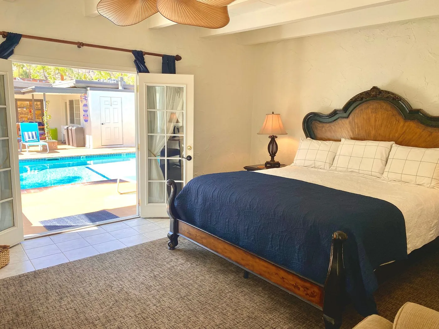 A bed covered in white and blue linens in a poolside room at Old Ranch Inn boutique hotel in Palm Springs, California