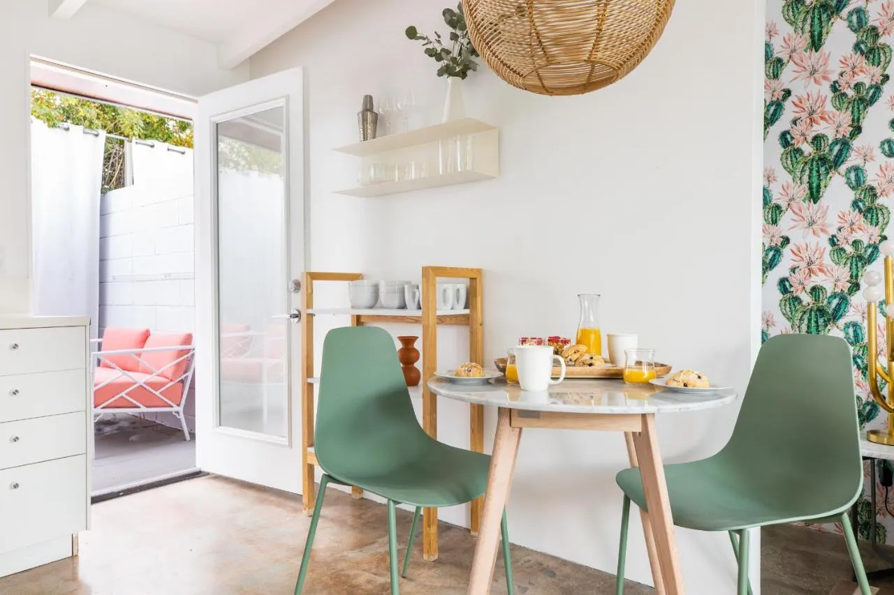 A white table and two green chairs in the large kitchen and dining space in a room at The Wesley Palm Springs