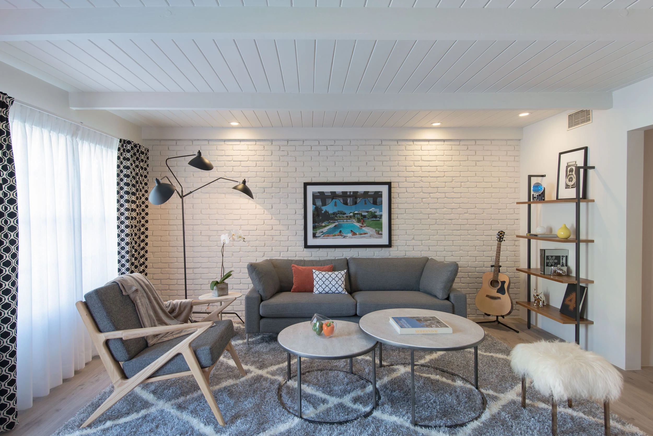 A gray and white rug with gray couches and white tables on top of it in a living room at The Weekend Palm Springs, with a Slim Aarons photograph on the wall