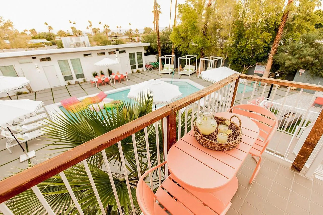 A pink table and chairs on a deck overlook the courtyard pool at The Wesley Palm Springs hotel