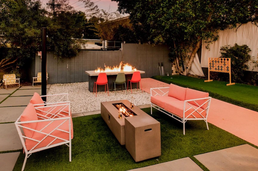 Two pink outdoor couches flank a firepit and table outside at night at The Wesley Palm Springs