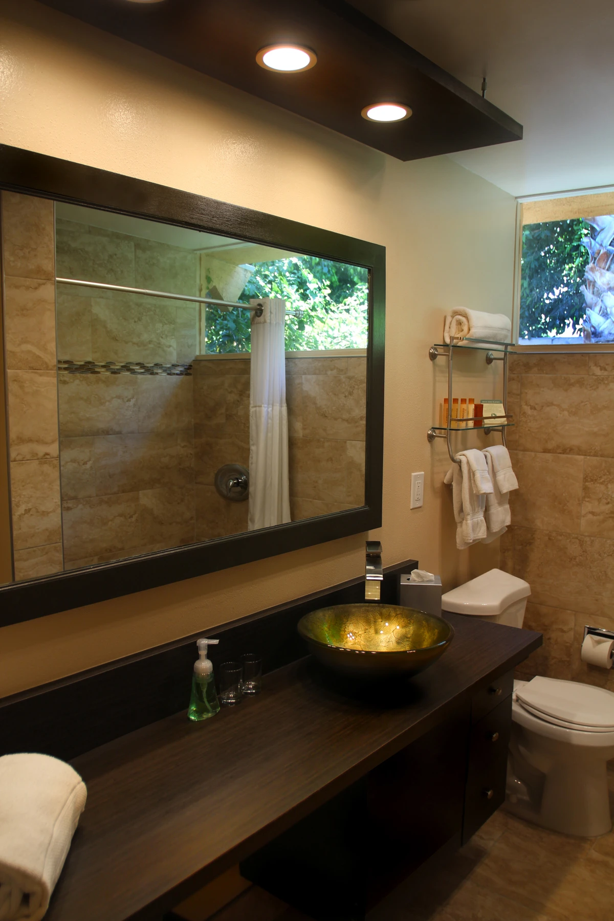 This bathroom at Triangle Inn Palm Springs has a gold bowl sink and a large tiled shower