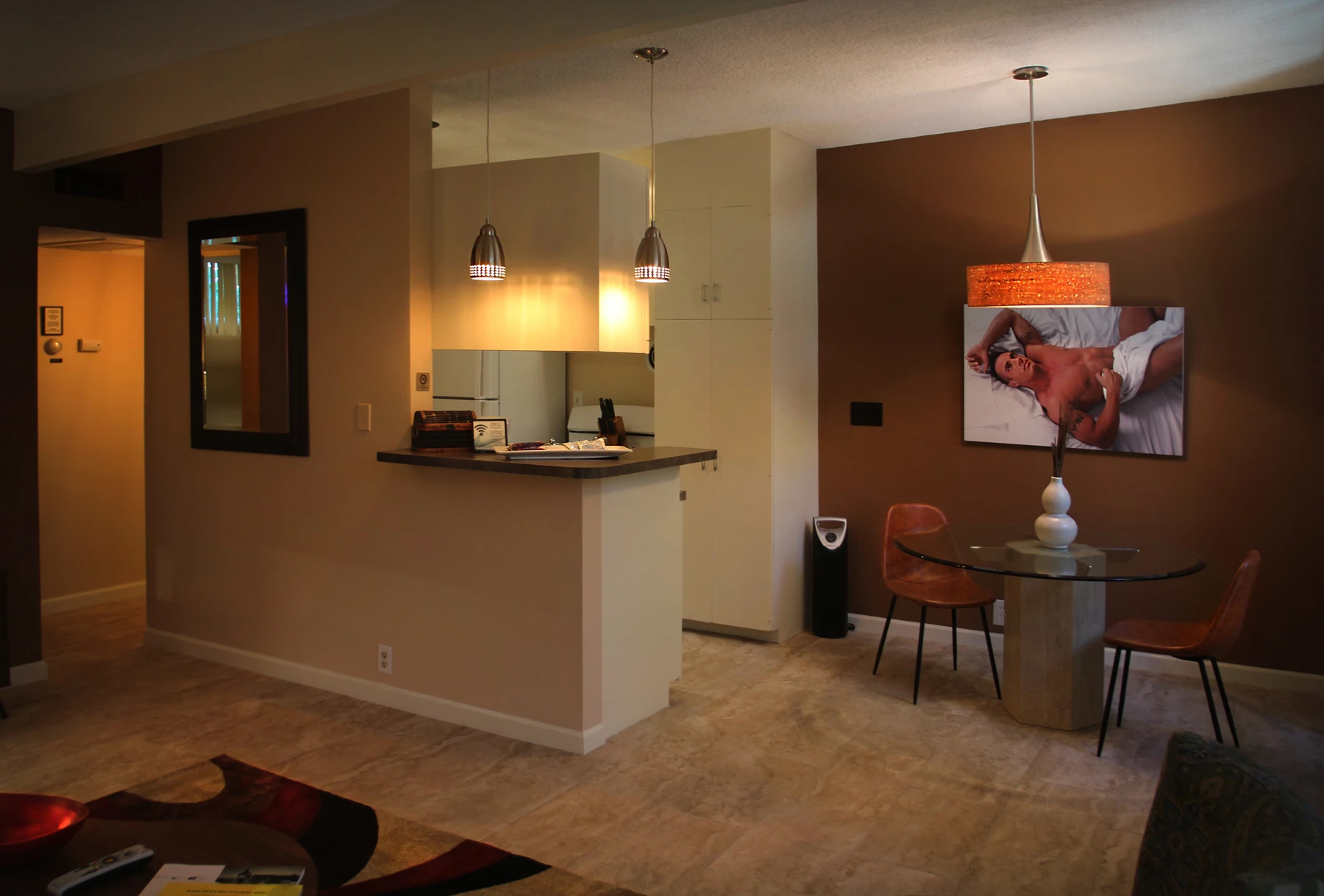 A table with two chairs underneath a photo of a man covered by a white towel at Triangle Inn Palm Springs