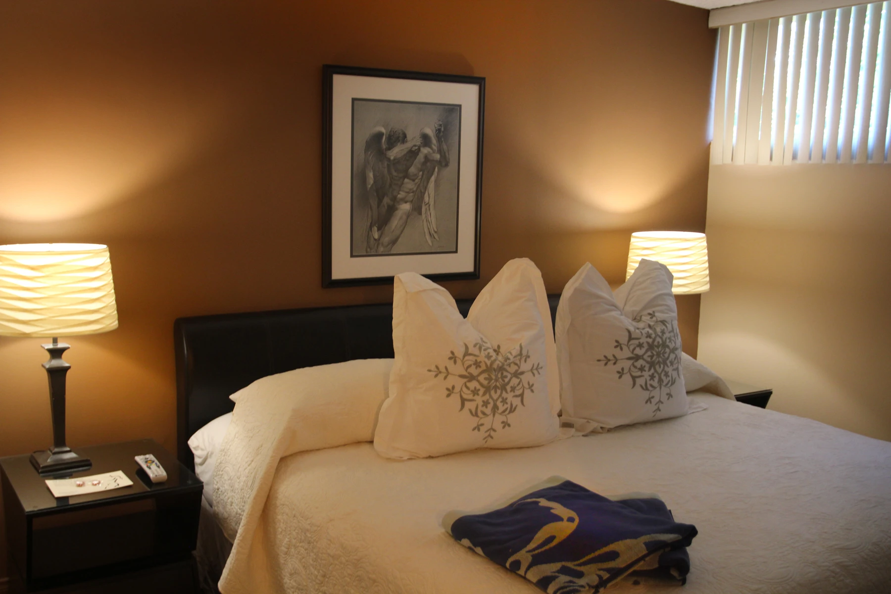 A bed with white linens and pillows and a blue towel at Triangle Inn Palm Springs