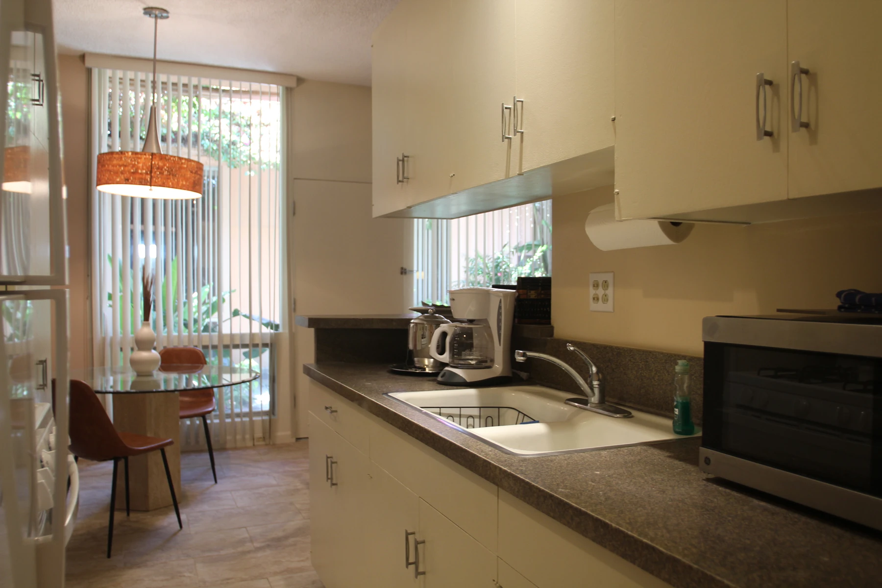 A kitchenette at Triangle Inn Palm Springs with a sink, microwave, coffee maker and table