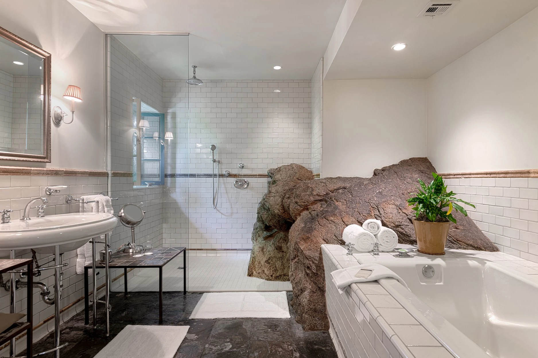 A natural rock is part of the landscape in a bathroom at The Willows Historic Palm Springs Inn