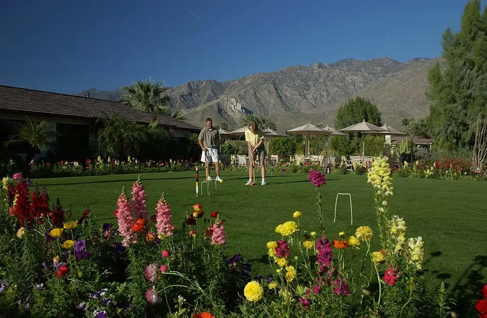 A man and a woman play croquet next to colorful snapdragons at Smoke Tree Ranch in Palm Springs, California