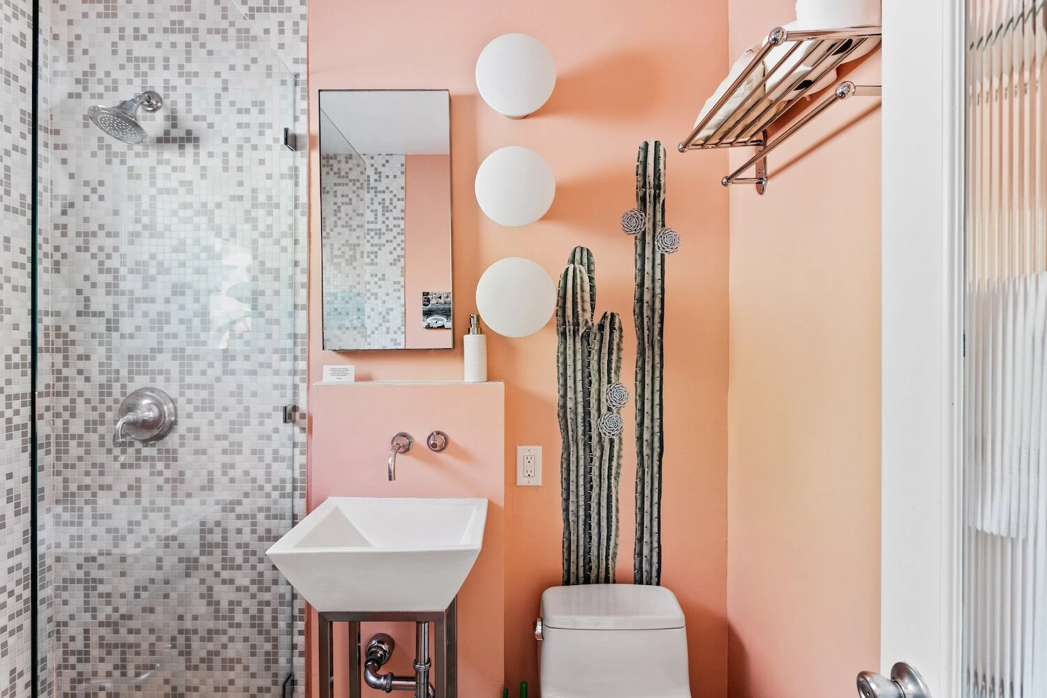 A bathroom at The Marley Palm Springs with peachy pink painted walls and a cactus painting