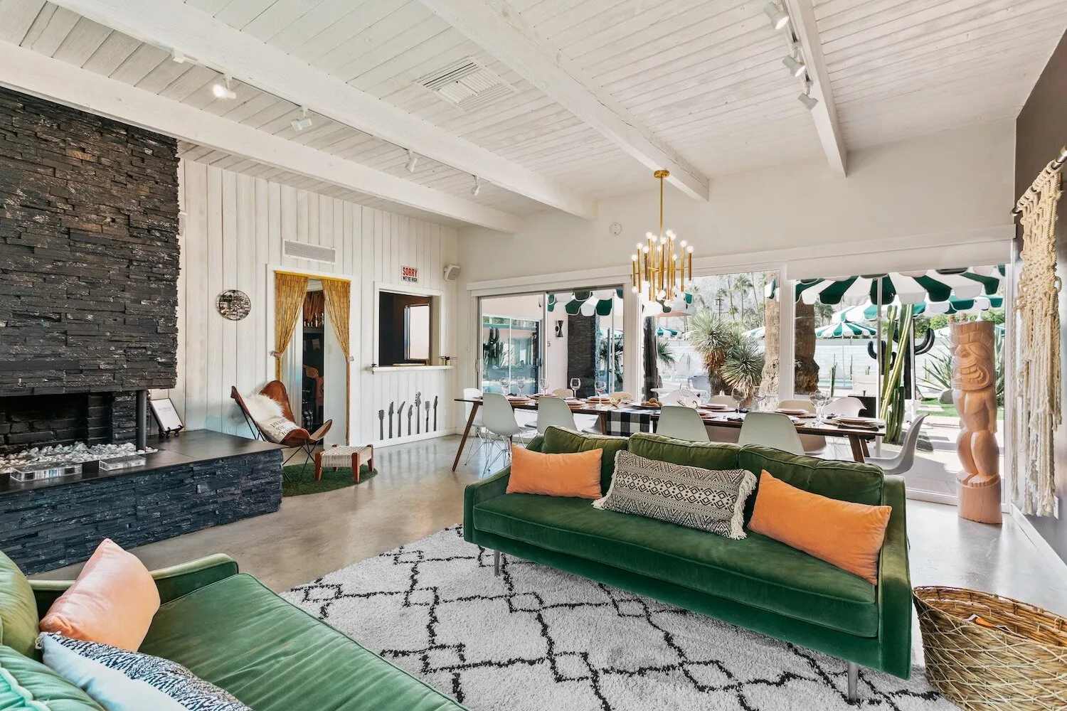 A green velvet couch with orange pillows on a geometric rug in the living room at The Marley Palm Springs