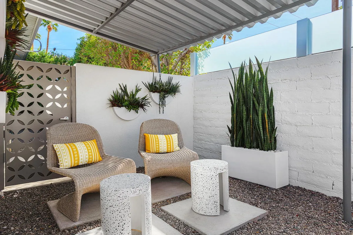 An outdoor patio at Limón Palm Springs with two chairs and green plants