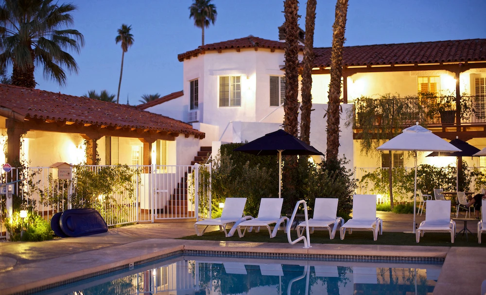 The lights glow around the sparkling pool at Alcazar Palm Springs