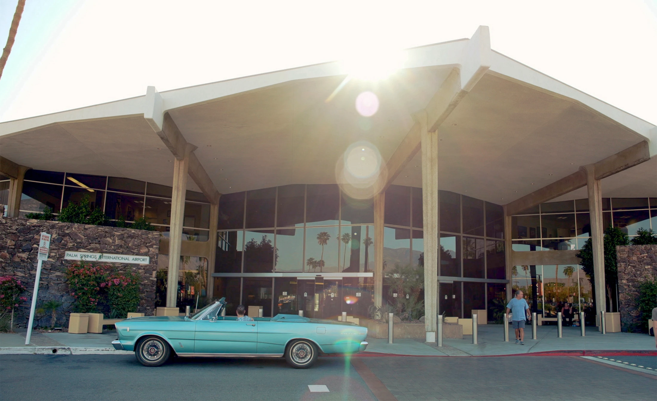 A vintage turquoise car sits in front of Palm Springs International Airport